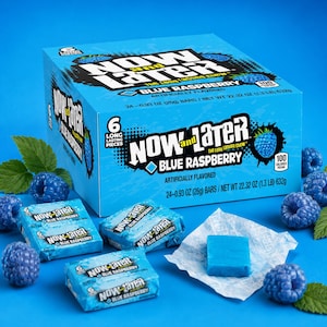 May include: A blue box of Now and Later Blue Raspberry candy containing 24 bars, with individual wrapped candy bars and loose blue raspberry pieces scattered around the box on a blue surface. The box displays the text Now and Later.