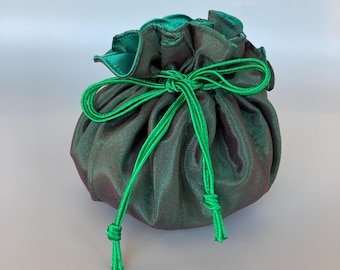 May include: A round, dark green pouch with a drawstring closure. The pouch is made of a shimmering fabric with a hint of red. The drawstring and the interior lining are a bright green color. The pouch is gathered at the top.