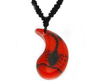 May include: A red and black yin yang pendant necklace with a scorpion design. The necklace is made of black cord.