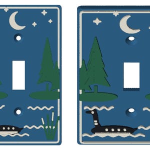 May include: Two rectangular light switch plates featuring a dark blue background with a night scene. The design includes a white crescent moon, stars, two green pine trees, a black goose swimming in wavy water, and green reeds on the side.