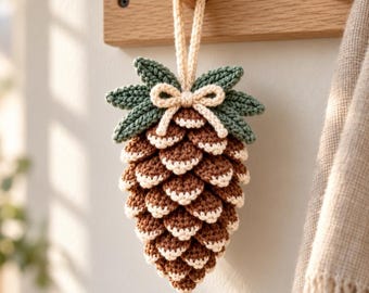 Patrón de ganchillo en PDF de piña, adorno navideño con punta nevada, hojas y lazo, decoración invernal de bosque.