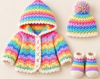 Puede incluir: Un conjunto de ganchillo que incluye una chaqueta con capucha, un gorro con pompón y un par de patucos. Cada pieza presenta un patrón ondulado de colores del arcoíris, con un borde festoneado blanco y botones blancos.