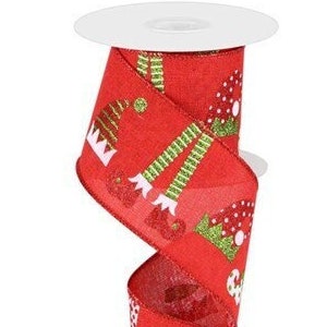 May include: Red ribbon with a repeating pattern of green and white elf legs and hats. The ribbon is on a spool.