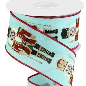 May include: A roll of 2.5 inch wide aqua blue ribbon with a red edge. The ribbon features a repeating pattern of nutcracker soldiers in red, gold, and black.