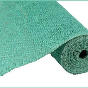 May include: A roll of turquoise burlap fabric. The fabric is tightly woven, with a visible texture. The roll is partially unrolled, revealing the fabric's thickness and the tightly wound core. The color is a solid, vibrant turquoise.