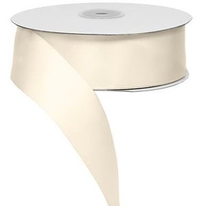 May include: A spool of ivory satin ribbon. The ribbon is 1.5 inches wide and is shown wrapped around a white cardboard spool.
