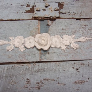 May include: White floral trim with a large rose in the center. The trim is made of a lightweight material and is perfect for adding a touch of elegance to any project.
