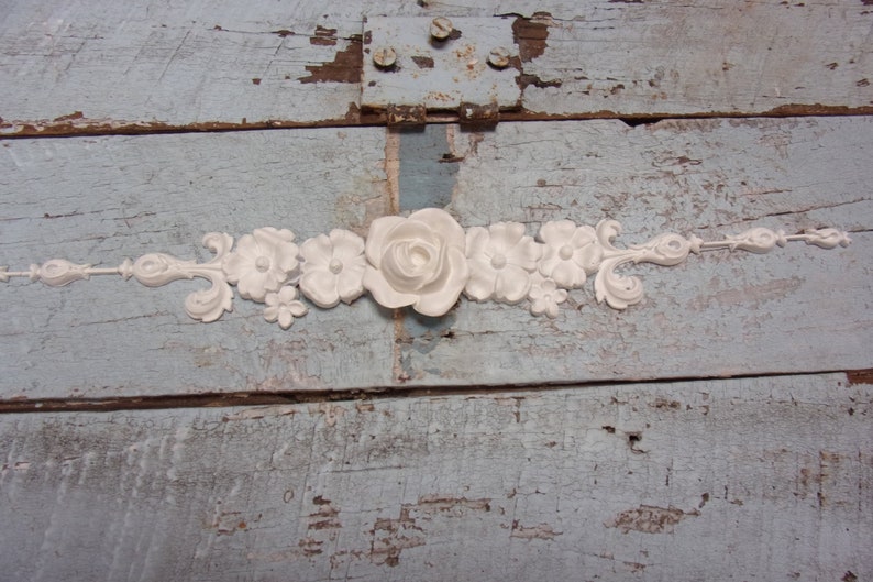 May include: White floral trim with a large rose in the center. The trim is made of a lightweight material and is perfect for adding a touch of elegance to any project.