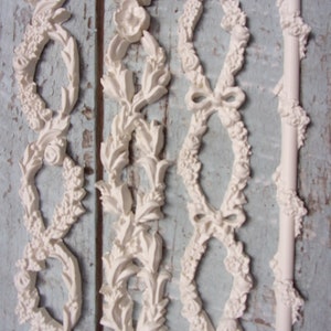 May include: Four white decorative trim pieces with floral and bow designs. The trim pieces are made of a lightweight material and are perfect for adding a touch of elegance to any project.