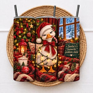 May include: A cylindrical tumbler featuring a festive Christmas scene with a white duck wearing a Santa hat and a red bow, wrapped in string lights. The design includes a decorated tree, a mug, and a pillow with the text Santa's favourite problem child.