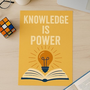 May include: A yellow poster with the words "KNOWLEDGE IS POWER" in large, white letters. The poster features an illustration of a lightbulb above an open book. A Rubik's cube, glasses, pencils, and scissors are on the table.