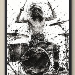 May include: A black and white ink splatter art print depicting a drummer with long hair playing a drum kit. The illustration features a shirtless figure holding drumsticks, surrounded by dynamic paint splashes and drips on a white background.