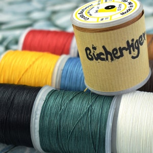 May include: Assortment of spools of thread in various colours, including red, yellow, black, green, and white. The spools are labelled "Bichertger" and "Made in the UK".
