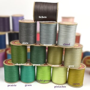 May include: A collection of colorful thread spools in various shades of green, grey, and brown. The spools are labeled with color names such as "lichen", "slate", "mouse", "cloud", "chartreuse", "green", "moss", "grey", "prairie", "grass", "light green", "pistachio", and "curry".