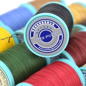 May include: Close-up of spools of waxed thread in various colours, including yellow, green, red, brown, and black. The spools are labelled "YUE FUNG Leather Sewing Waxed Thread" and "www.yuefungbutton.com".