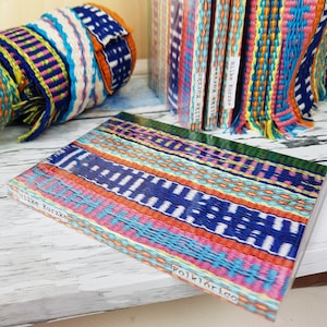 May include: A colourful notebook with a woven pattern on the cover. The cover is titled "Folklorico" and has the name "Hilke Kurzke" printed on the spine.