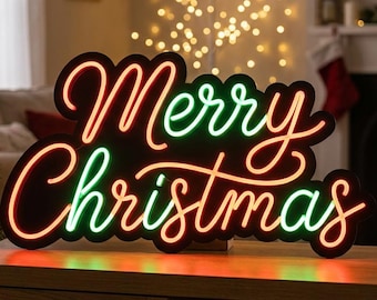 Può includere: Un'insegna nera con la scritta Merry Christmas in corsivo, illuminata da tubi al neon rossi e verdi. L'insegna è posizionata su una superficie in legno, accanto a un albero di Natale decorato e a una statuetta di Babbo Natale.