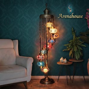 May include: A tall floor lamp with a dark metal stand featuring nine hanging glass mosaic globes in various colors including blue, red, orange, and white. The lamp has a decorative top finial and the text Arenahouse is visible above.