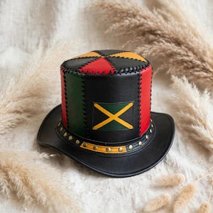 May include: A top hat constructed from panels of black, red, green, and yellow leather. The crown features a central yellow cross on a green background. The base is adorned with a band of metallic studs and decorative stitching.