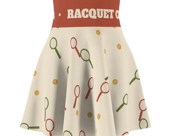 Può includere: Una gonna a ruota a vita alta color crema con un motivo ripetuto di racchette da tennis rosse e verdi e palline da tennis gialle. L'ampia fascia in vita rossa presenta la scritta bianca RACQUET CLUB in caratteri maiuscoli.