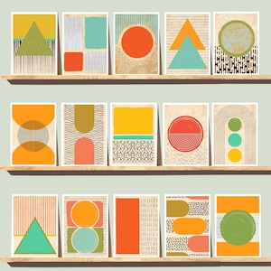 May include: A collection of abstract art prints displayed on wooden shelves. Each print features geometric shapes in vibrant colors like orange, teal, yellow, and green. Designs include circles, triangles, and rectangles with patterned backgrounds.