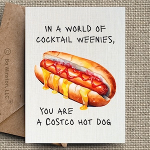 May include: Greeting card with a watercolor illustration of a hot dog on a bun, topped with ketchup and melted cheese. The text reads, "In a world of cocktail weenies, you are a Costco hot dog."
