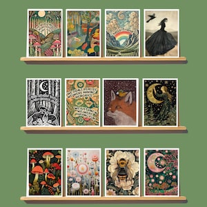 May include: A collection of art prints displayed on wooden shelves against a green background. The prints feature various illustrations, including landscapes, animals, and inspirational quotes. The color palette includes earthy tones, blues, and greens. Some prints have text that reads "hello, friend" and "The world needs more souls like you."