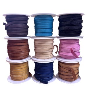 May include: Nine spools of leather cord in various colors, including black, blue, brown, tan, pink, and teal. The cords are wound around white spools.