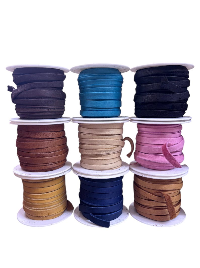 May include: Nine spools of leather cord in various colors, including black, blue, brown, tan, pink, and teal. The cords are wound around white spools.