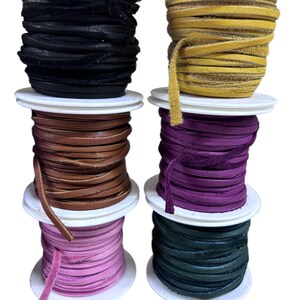 May include: Six spools of leather cord in different colors: black, yellow, brown, purple, pink, and green. The spools are stacked on top of each other.