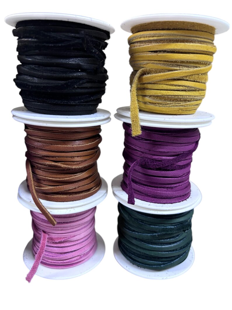 May include: Six spools of leather cord in different colors: black, yellow, brown, purple, pink, and green. The spools are stacked on top of each other.
