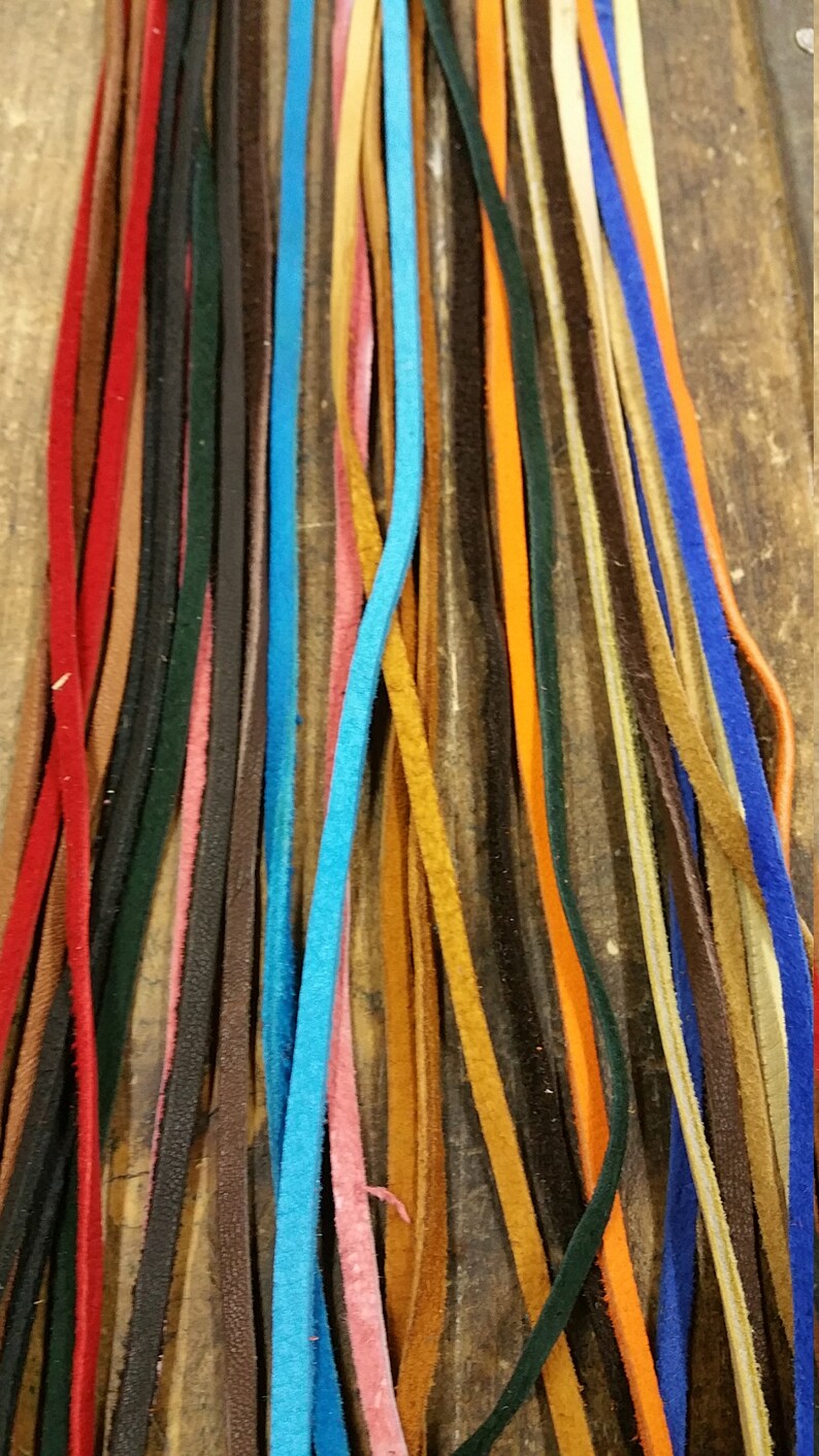 K&ouml;nnte beinhalten: Eine Sammlung von Lederb&auml;ndern in verschiedenen Farben, darunter Rot, Blau, Braun, Orange und Gr&uuml;n. Die B&auml;nder sind vertikal angeordnet, wobei die Enden der B&auml;nder am unteren Rand des Bildes ausgerichtet sind.