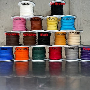 May include: A collection of 15 spools of leather cord in various colors, including white, pink, tobacco, gold, turquoise, chocolate, whiskey, black, saddle, smoke, blue, orange, green, red, gray, and purple.
