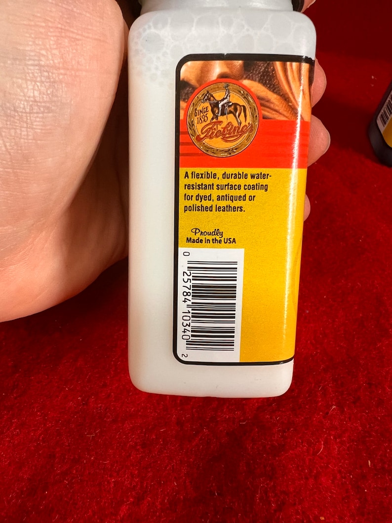 May include: A white bottle with a yellow label that says "Since 1895 Bosine". The label also says "A flexible, durable water-resistant surface coating for dyed, antiqued or polished leathers." and "Proudly Made in the USA". There is a barcode on the label.