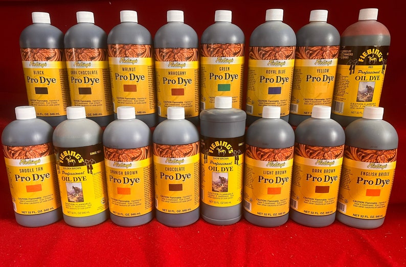 May include: A collection of 16 bottles of Fiebing's leather dye in various colors, including black, brown, red, green, blue, and yellow. The bottles are labeled with the color name and "Pro Dye" or "Oil Dye".