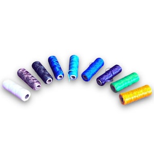 May include: A set of ten spools of thread in various shades of blue, green, yellow, white, and gray. The spools are arranged in a semi-circle on a white background.