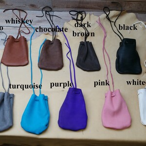 May include: Ten leather pouches in various colors, including tobacco, whiskey, chocolate, dark brown, black, gray, turquoise, purple, pink, and white. Each pouch has a drawstring closure and a long cord for carrying.