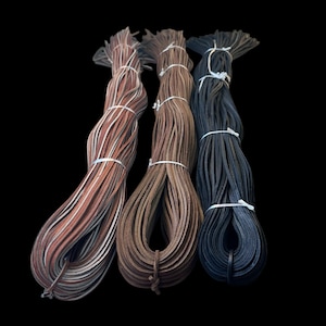 May include: Three spools of leather cord in different colors: brown, tan, and black. The cords are wrapped and tied together.
