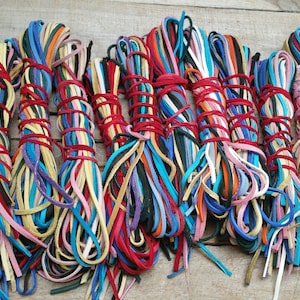 May include: A bundle of colorful leather cords, tied together with red string. The cords are various shades of blue, green, yellow, pink, red, orange, and brown.