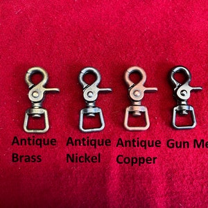 May include: Four metal swivel snap hooks in different finishes: antique brass, antique nickel, antique copper, and gun metal.
