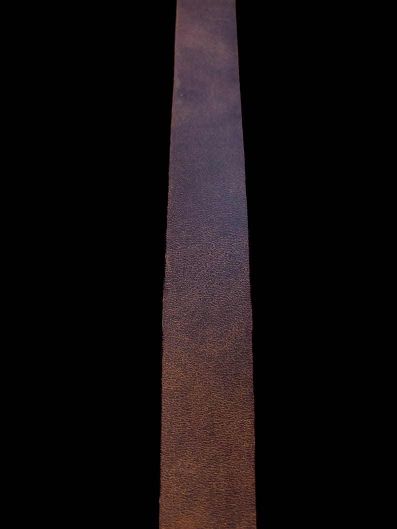 May include: A long, narrow strip of brown leather with a textured surface.