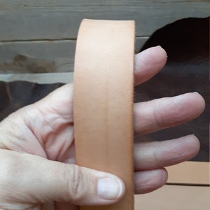 May include: A close-up of a light brown leather strip. The leather is smooth and appears to be of high quality.