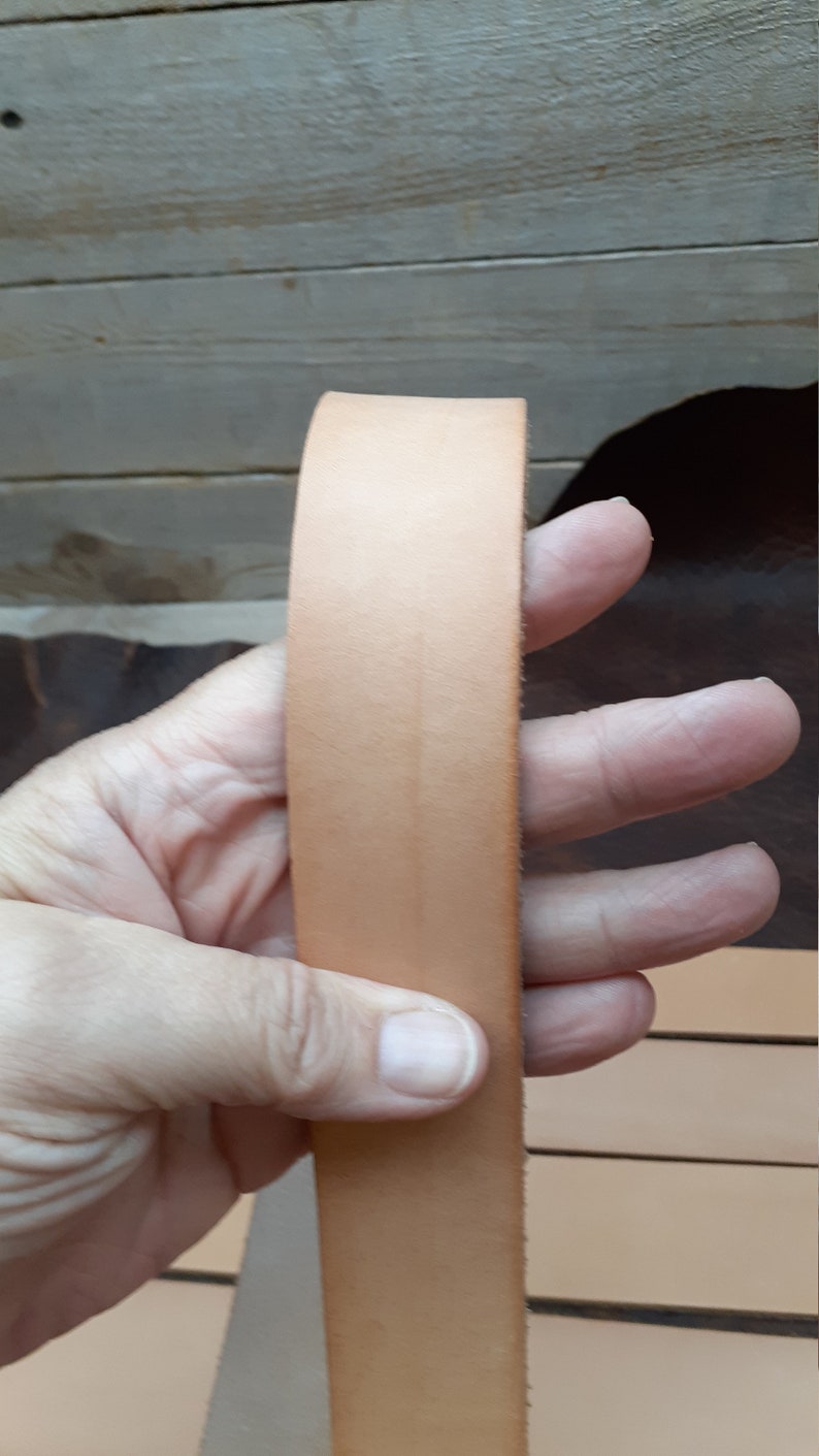 May include: A close-up of a light brown leather strip. The leather is smooth and appears to be of high quality.