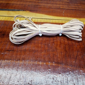 K&ouml;nnte beinhalten: Eine Rolle aus nat&uuml;rlichem Lederband, mit einem wei&szlig;en Gummiband zusammengebunden. Das Band ist etwa 6 mm breit und eignet sich ideal f&uuml;r Lederbastelprojekte.