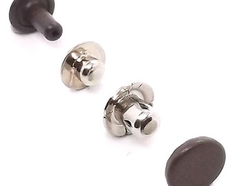 Könnte beinhalten: Drei Metall- und Kunststoff-Druckknöpfe in verschiedenen Farben: Silber, Braun und Schwarz. Die Druckknöpfe werden zum Befestigen von Stoff oder Leder verwendet.