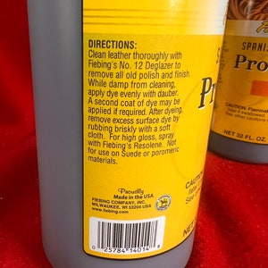May include: A yellow and black bottle of Fiebing's No. 12 Deglazer leather cleaner. The bottle is labeled with directions for use and a warning about flammability. The bottle is made in the USA and has a barcode.