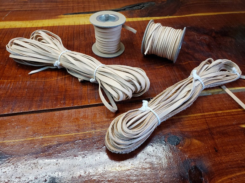 K&ouml;nnte beinhalten: Drei Spulen mit hellbraunem Lederband, zwei sind lose und eine ist auf einer Spule. Das Band ist etwa 6 mm breit.