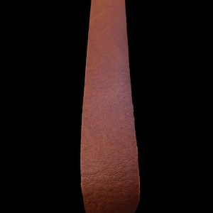 May include: A long strip of brown leather with a textured surface.