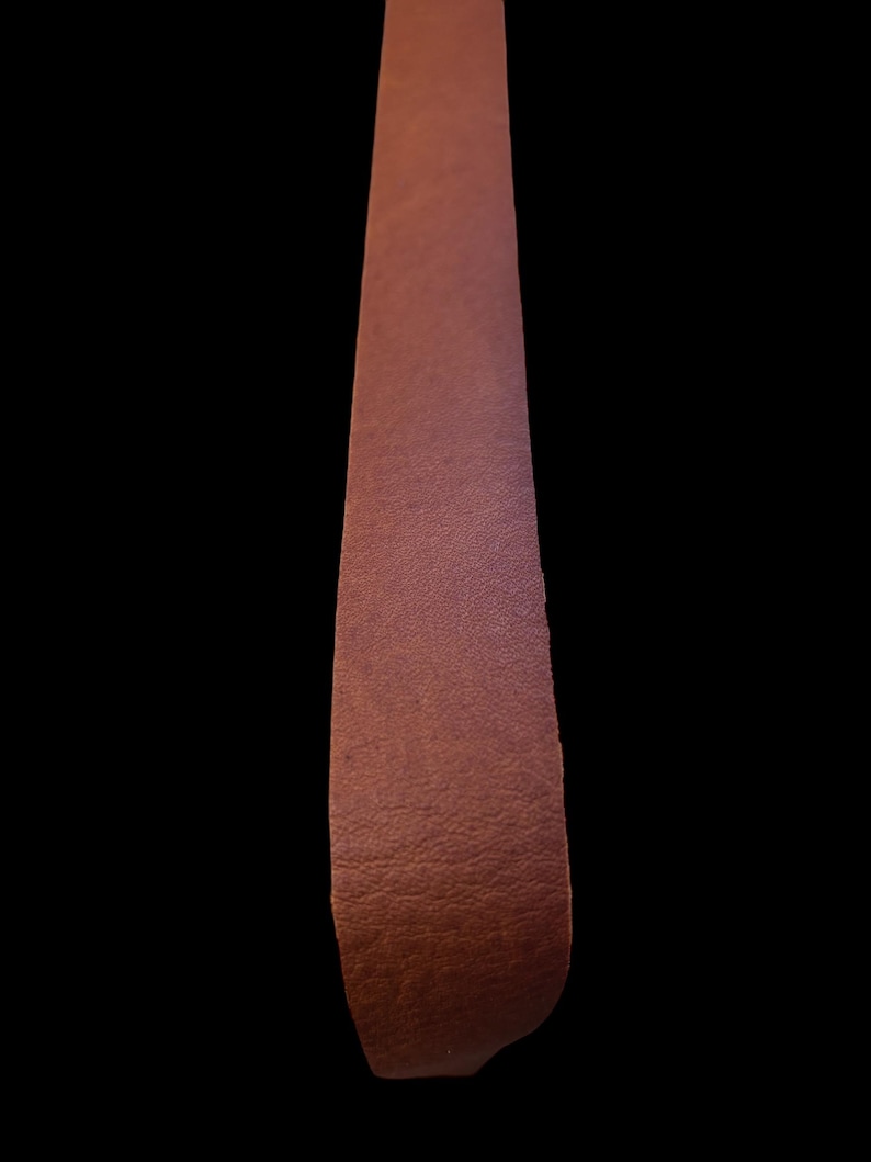May include: A long strip of brown leather with a textured surface.