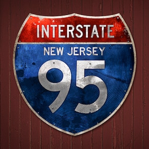 May include: A distressed metal sign for Interstate 95 in New Jersey. The sign is shield-shaped with a red top, blue center, and white lettering. The text reads "INTERSTATE", "NEW JERSEY", and "95". The sign is mounted on a weathered, reddish-brown wooden surface.